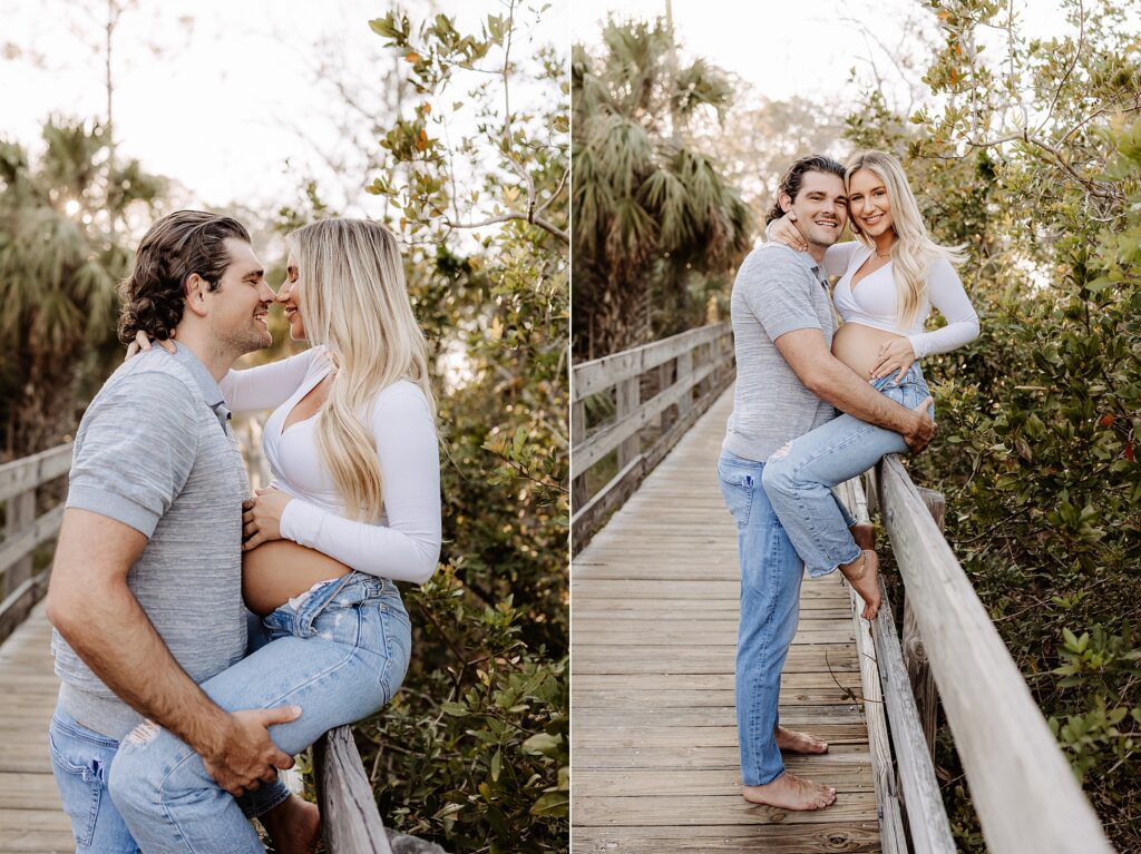 Playful maternity moment on a wooden boardwalk in Holiday, Florida, with a partner lifting his pregnant wife as they laugh together in the trees.