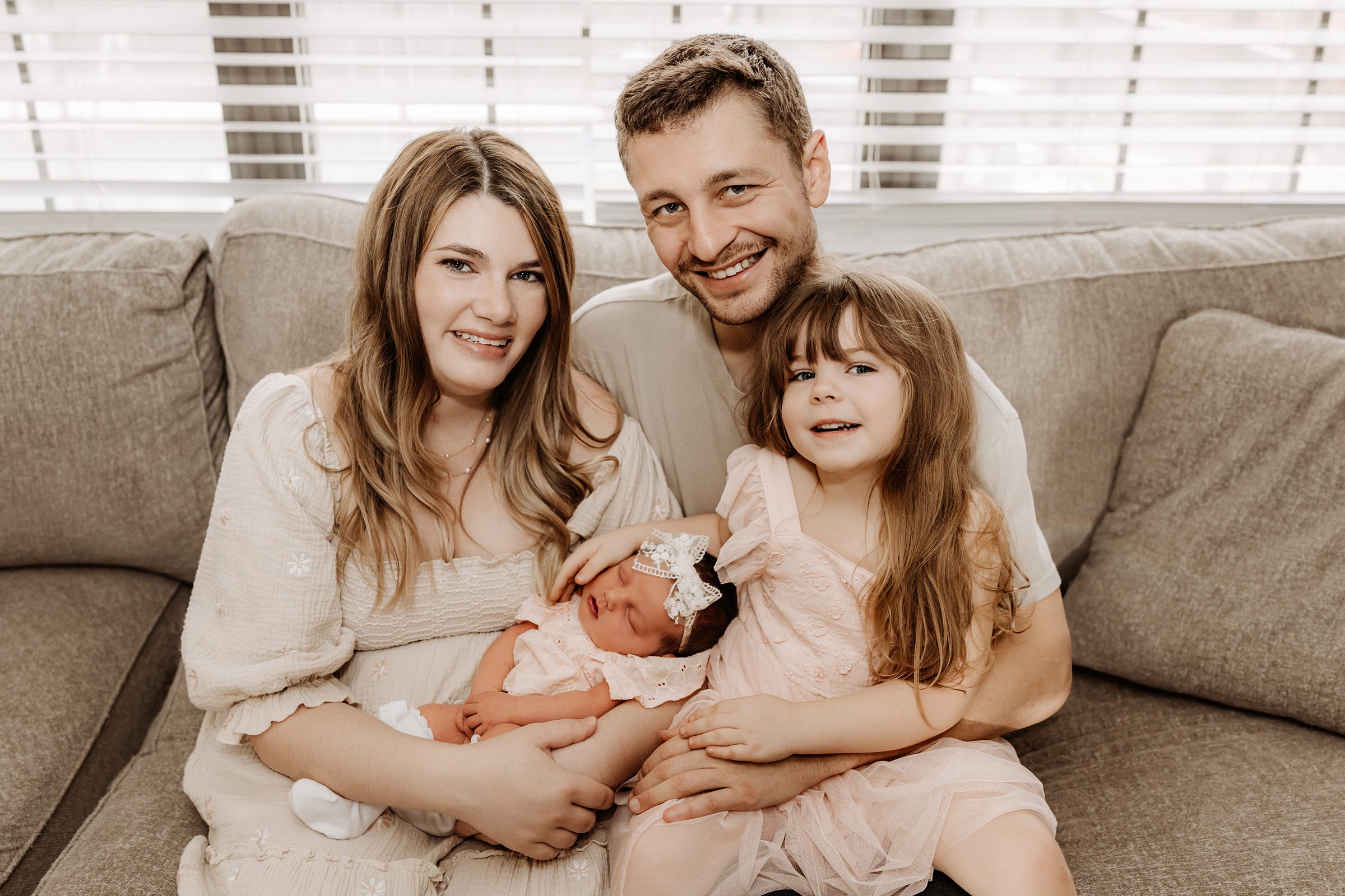 Lifestyle family portrait on living room couch with newborn and toddler during in-home newborn session in Tampa Florida