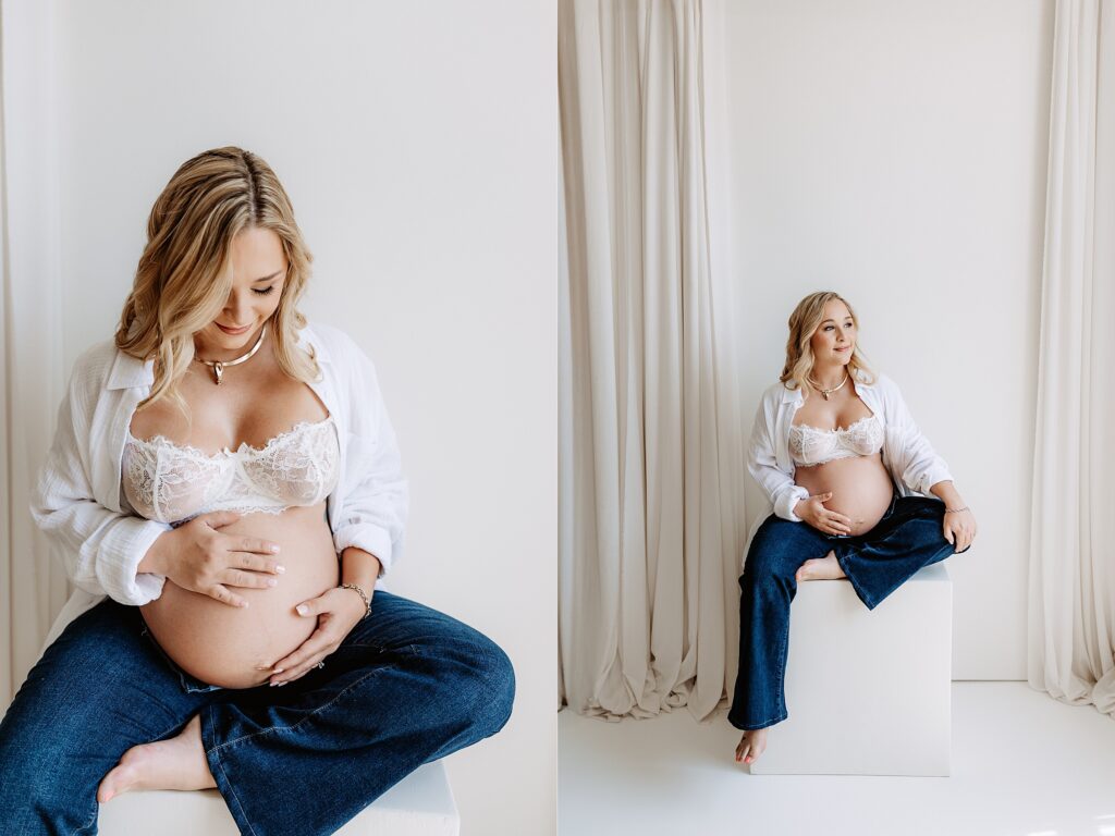 Maternity portrait of pregnant woman in lace bra and jeans sitting and cradling belly in minimalist Tampa studio