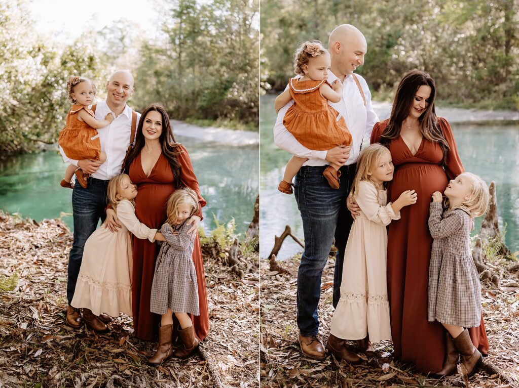 Full family of five, including pregnant mom, dad, and three daughters, snuggled together beside sparkling blue spring water

