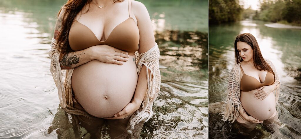 Maternity portrait of woman in tan swimwear, gently holding belly while standing in calm, clear river during golden hour