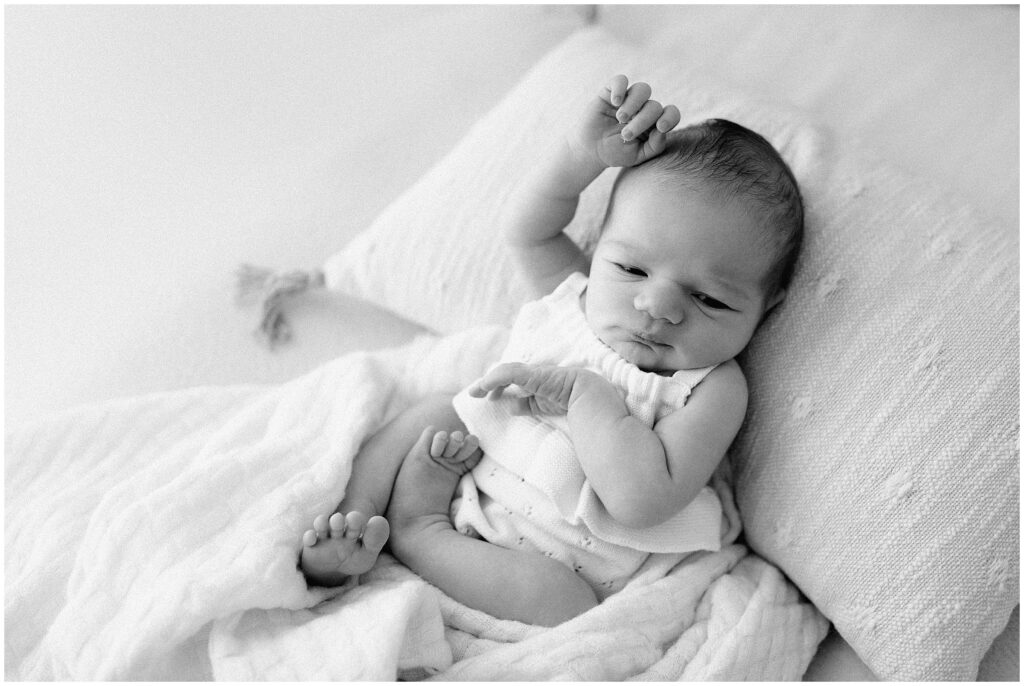 Adorable 1-week-old baby girl wrapped in delicate white lace wraps with a matching headband, captured during a newborn photoshoot