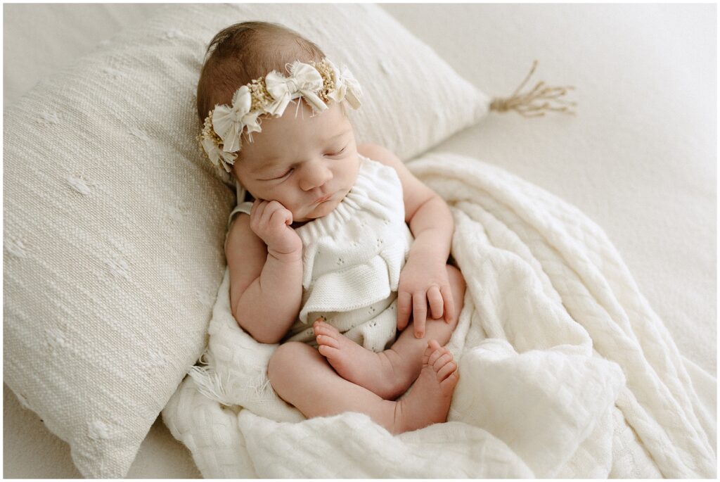 Close-up of newborn baby girl wearing a sweet white dress, showcasing innocence and purity in a boho-styled studio setting