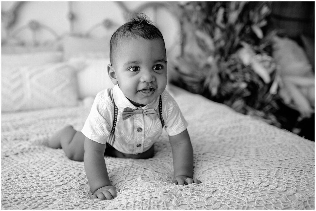 black and white portrait of little boy smiling and crawling on bed at springhill florida photography studio