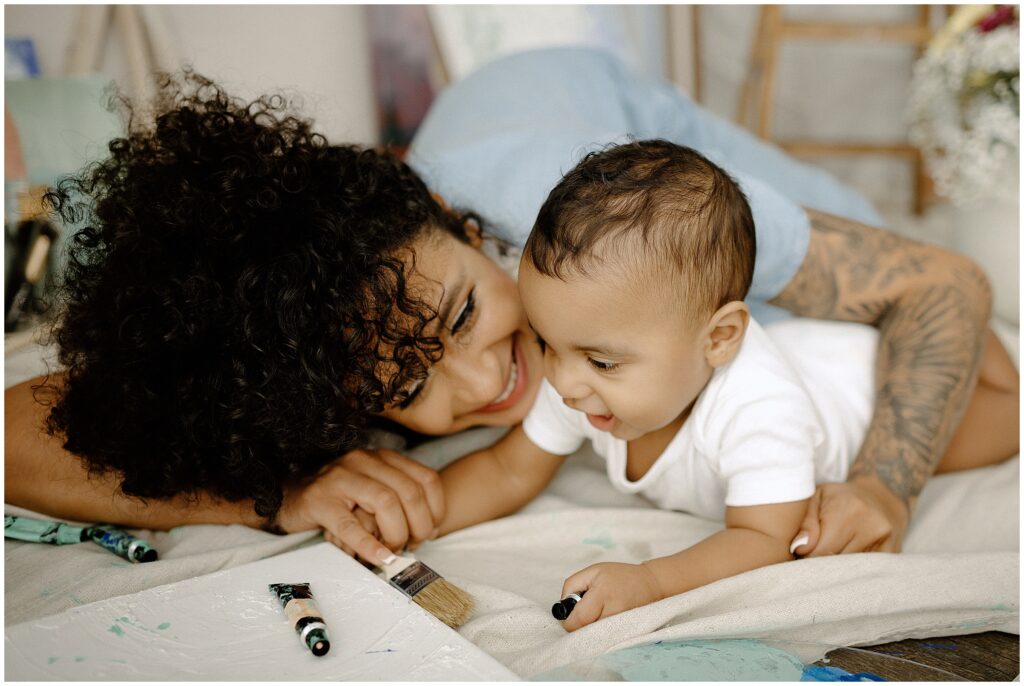 Joyful mom and son using blue paint and brushes at springhill florida photography studio