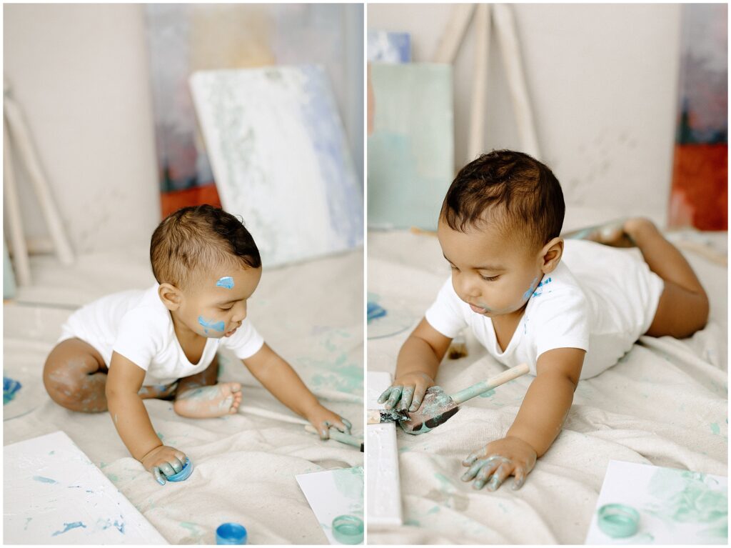 Happy toddler using a paintbrush and blue paint at springhill florida photography studio