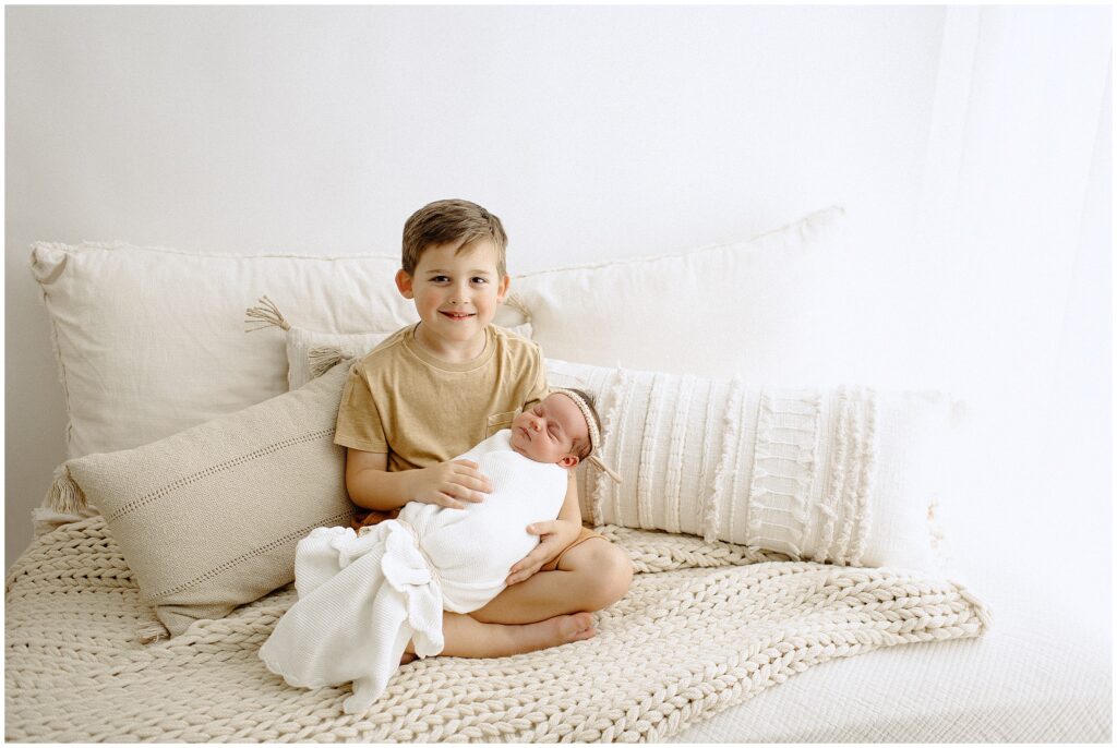 Brother gently holding his newborn sister at springhill florida photography studio