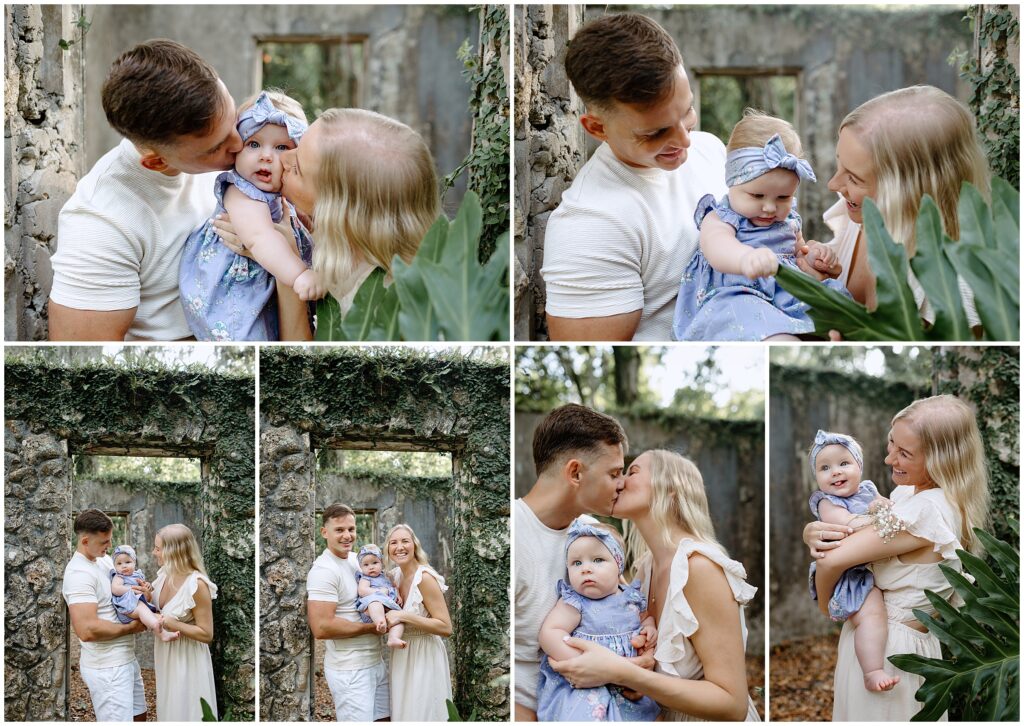 Baby in a blue and white floral dress being kissed by both mom and dad in front of ruins
