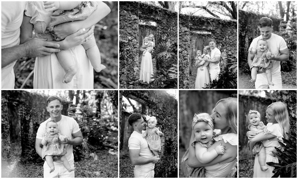 black and white photo of Baby in a blue and white floral dress being kissed by both mom and dad, creating a loving family moment.
