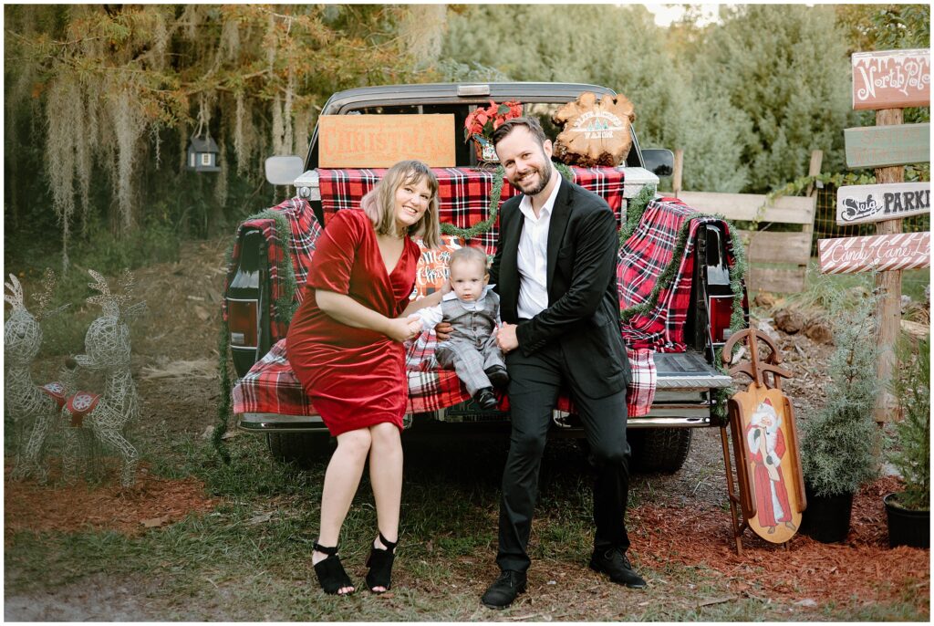 Family enjoying a festive day among Christmas trees and sitting in a truck with decor at Blue Acres in Shady Hill, Florida.