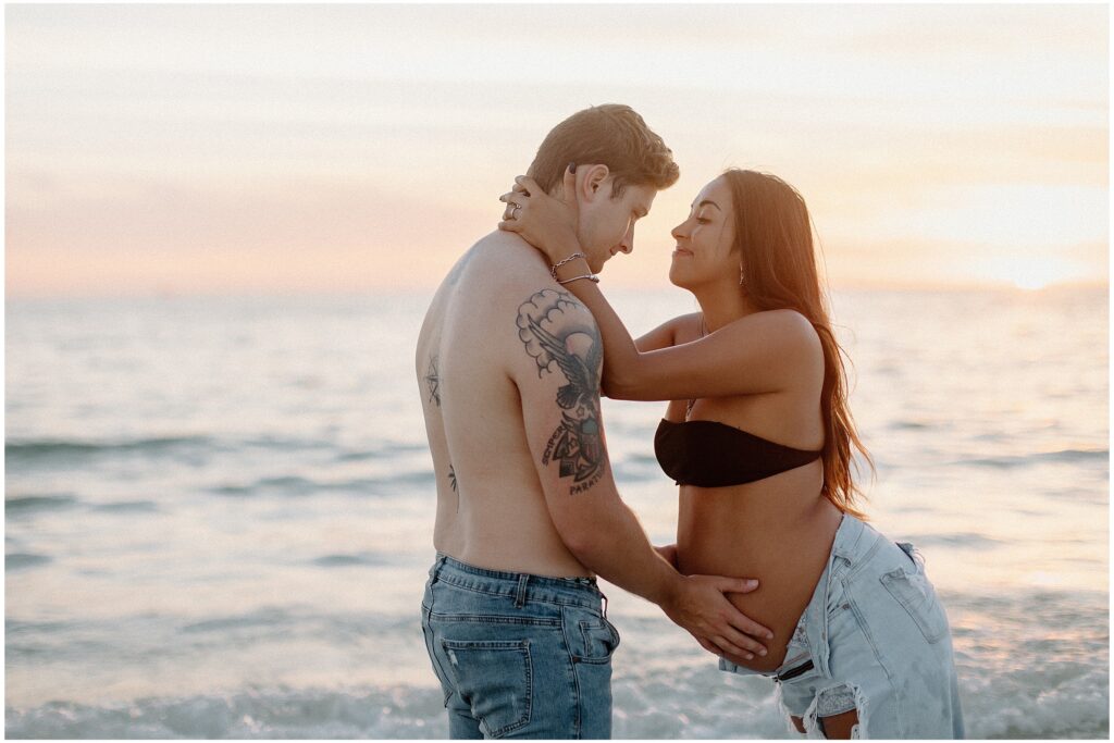 Close up portrait of mom and dad wearing jeans in ocean at maternity session in springhill florida