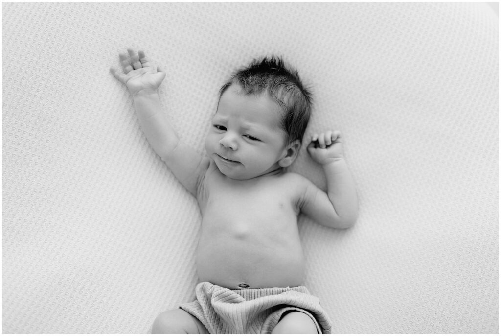 Black and white image of newborn baby stretching arms during a Spring Hill, FL photo shoot