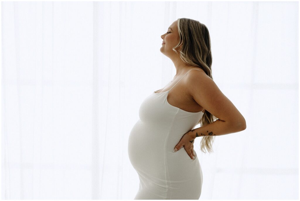 Close up portrait during maternity session with blonde woman in white dress with white background at Spring Hill Studio