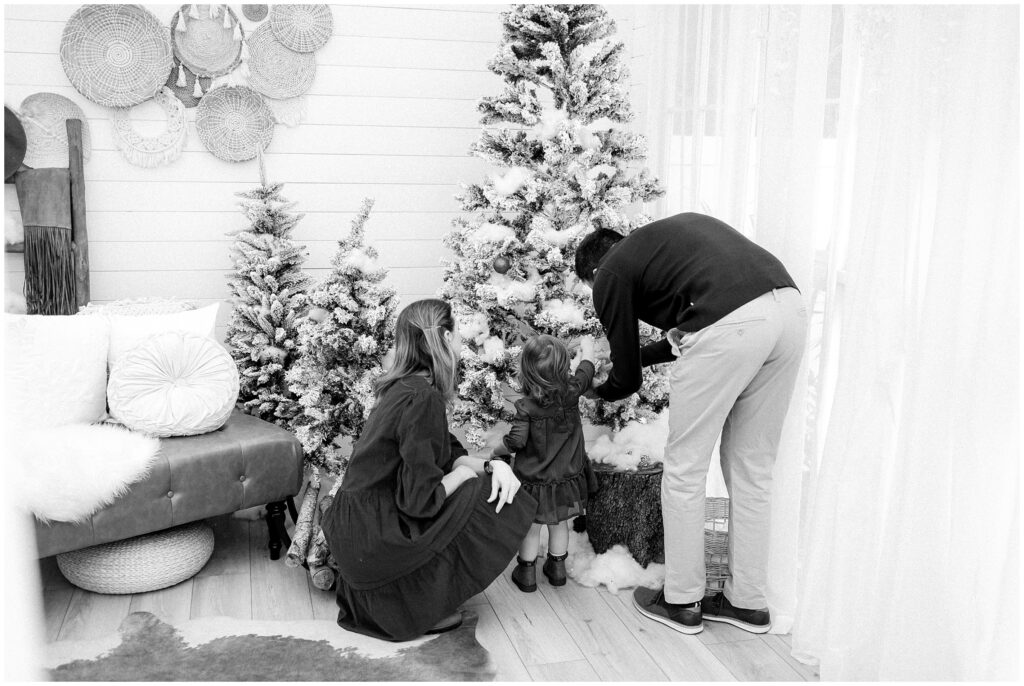 Black and white photo of family hanging christmas ornaments in Tampa's Winter Wonderland Cottage