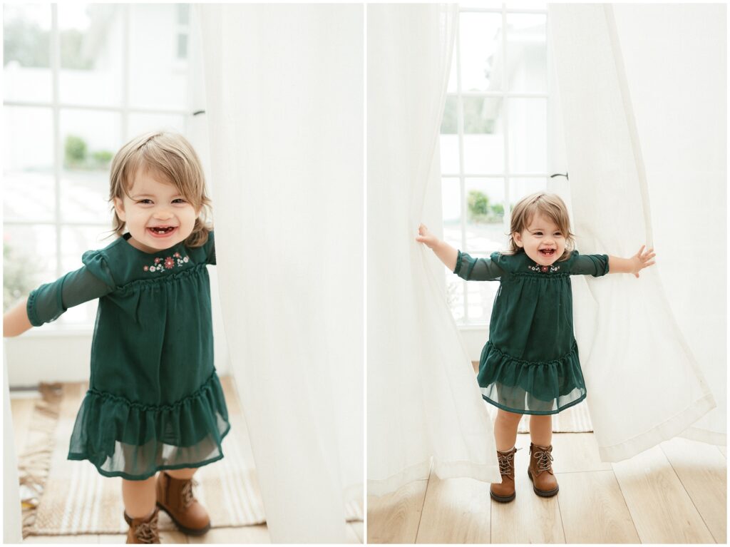 Little girl in green dress playing in white curtains and smiling in holiday-themed session in Tampa