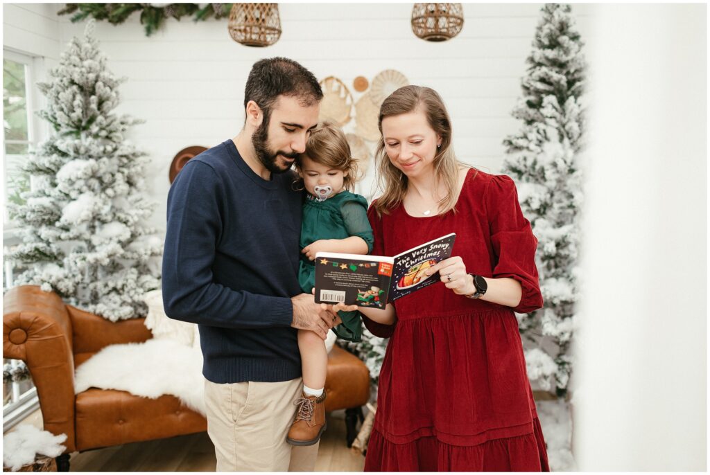 Mom and dad with daughter reading a book in Christmas-themed session in Tampa