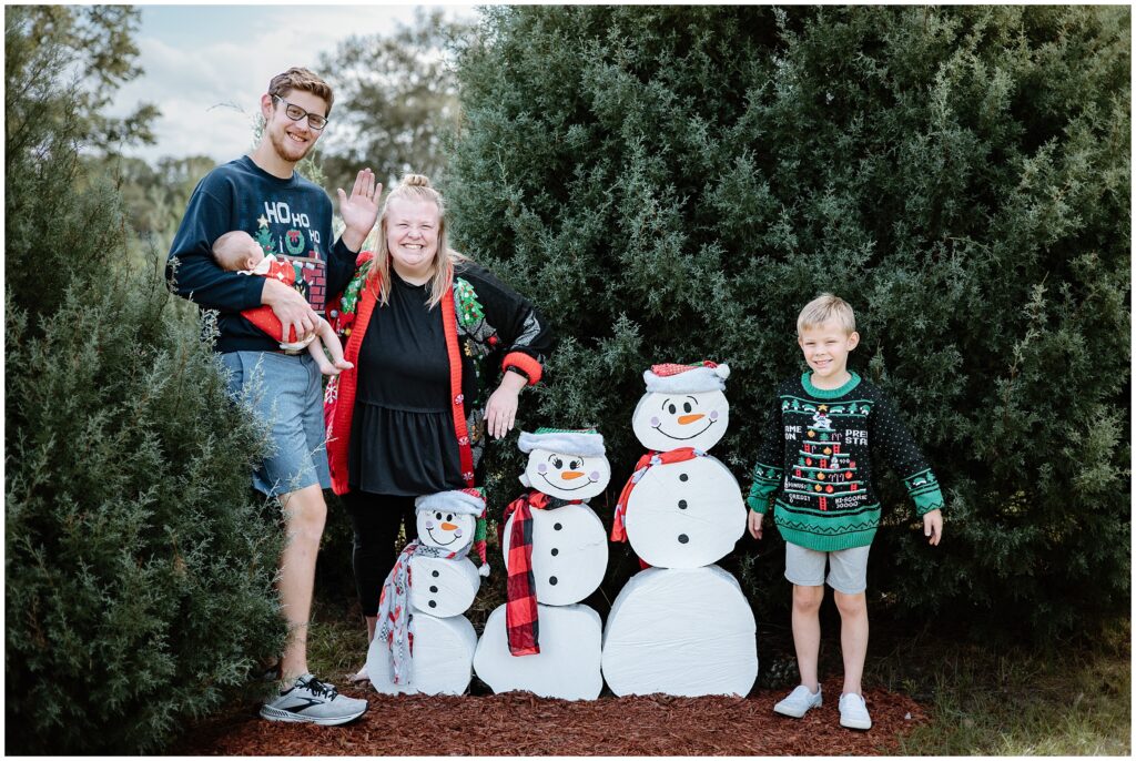 Family having fun posing with wooden snowmen at Blue Acres Christmas Tree Farm in Tampa