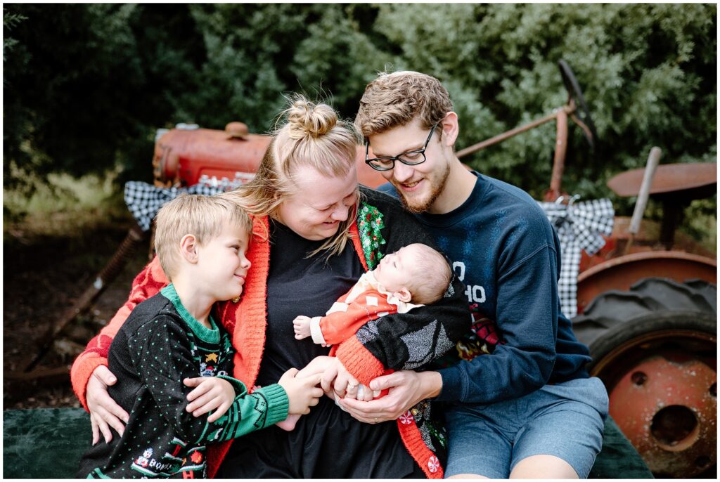 Mom and dad with little boy and baby girl by tractor at Blue Acres Christmas Tree Farm in Tampa