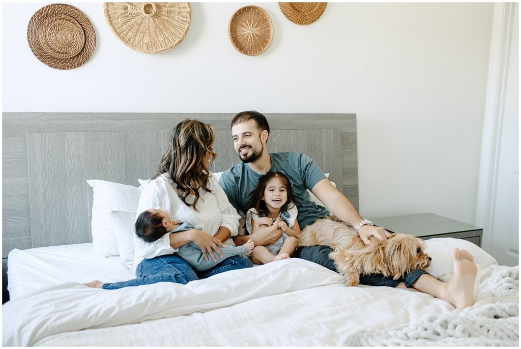 Family with dog cuddling on the bed during newborn lifestyle session