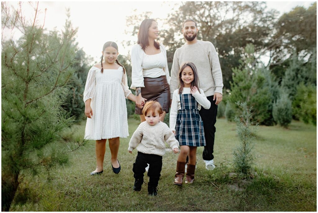 Family of 5 walking next to baby trees at Blue Acres Christmas Tree Farm in Florida