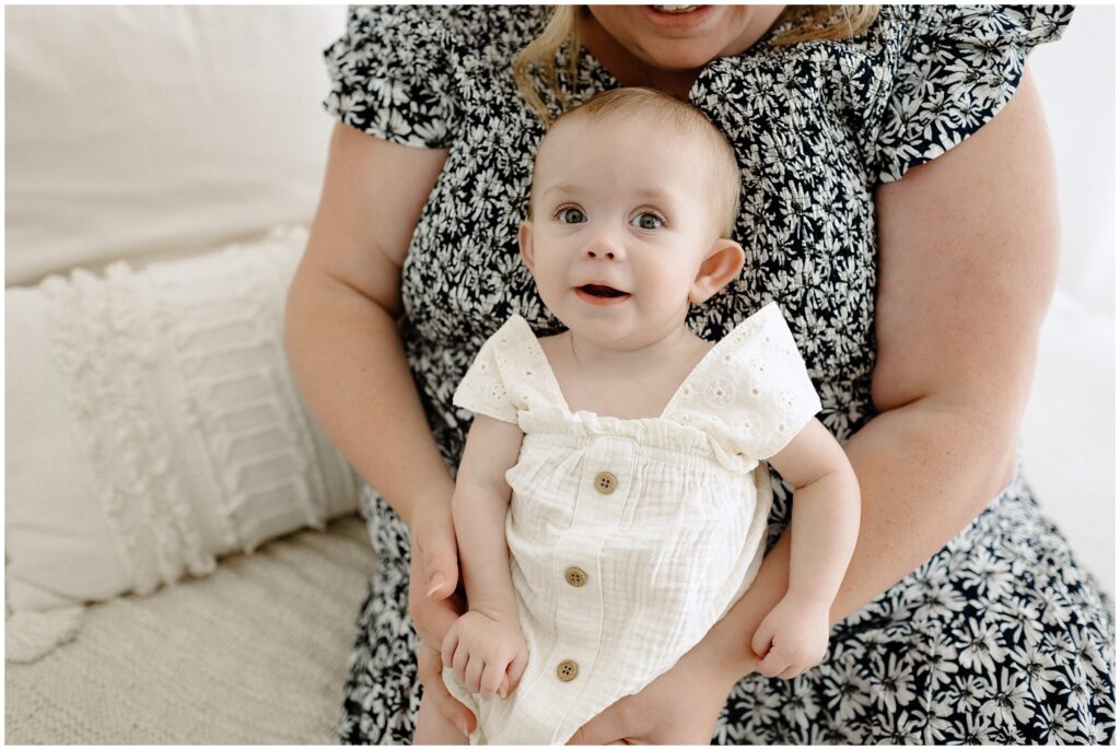 Close up portrait of little girl sitting on mom's laugh during milestone family session Spring Hill Studio in Florida