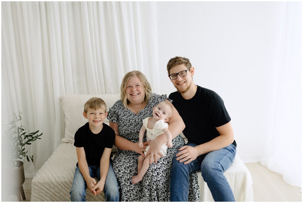 Family portrait of mom, dad, little girl, and big brother smiling at Spring Hill Studio in Florida