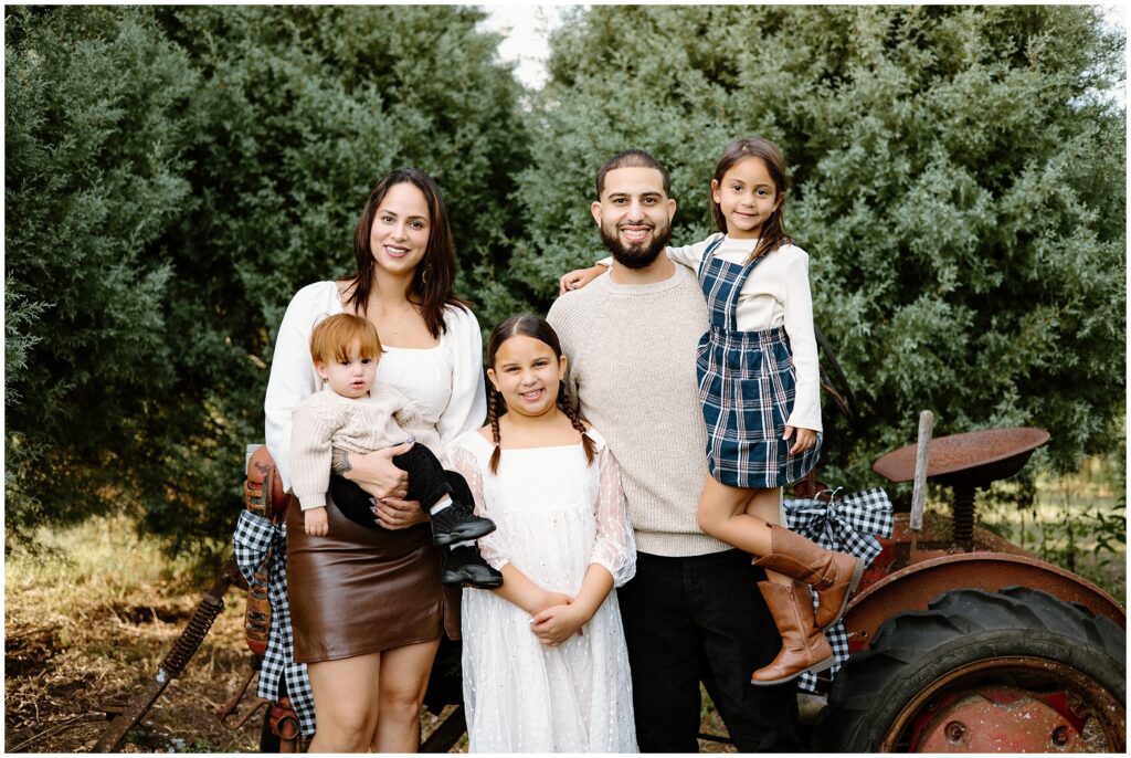 Family of 5 sitting on tractor next to trees at Blue Acres Christmas Tree Farm in Florida