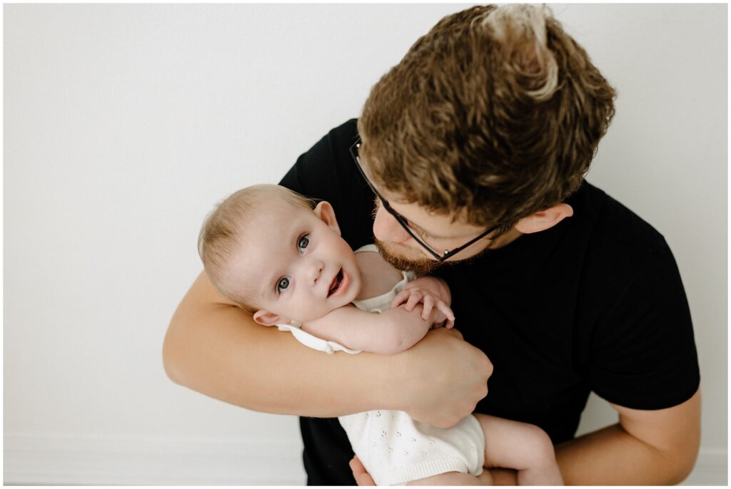 Dad snuggling with little girl looking at camera during family milestone session Spring Hill Studio in Florida