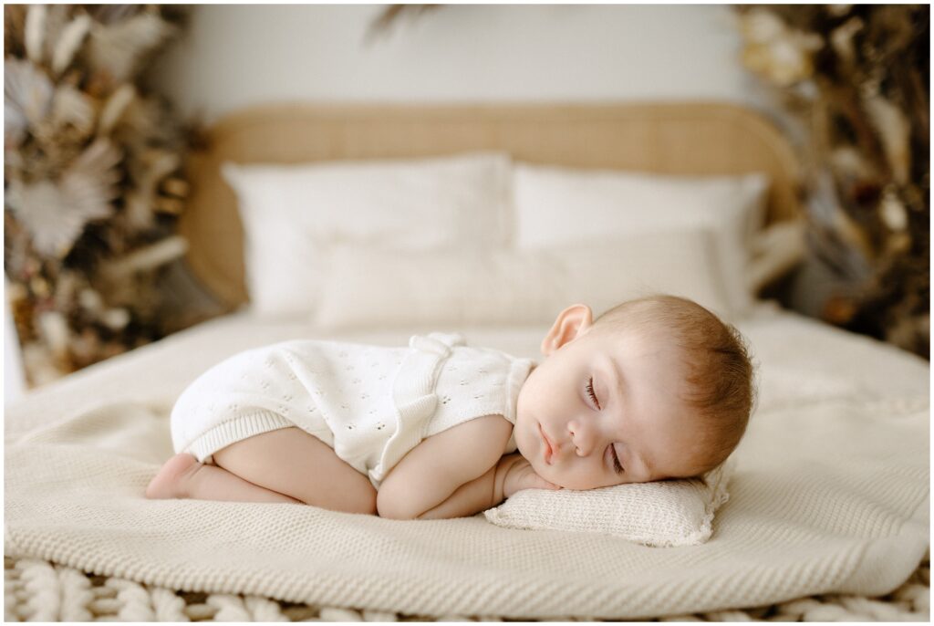 Sleeping baby girl in white knit outfit on beige blankets Spring Hill Studio in Florida