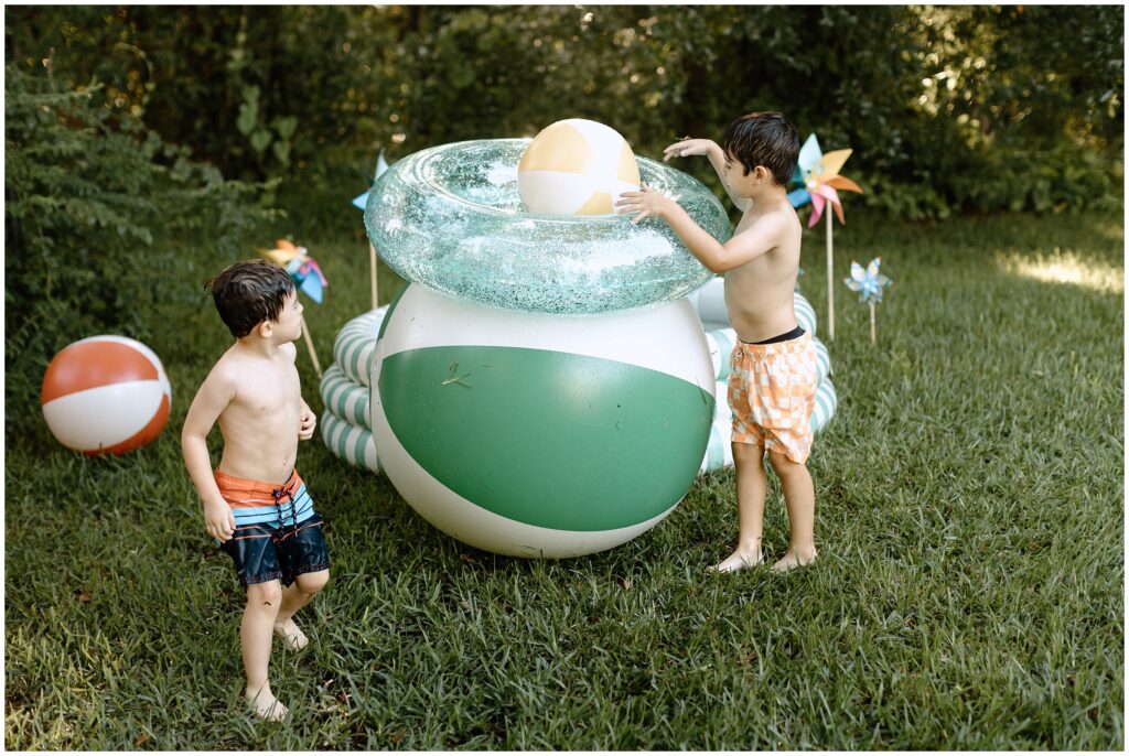 Brothers playing with colorful blow-up balls in the water