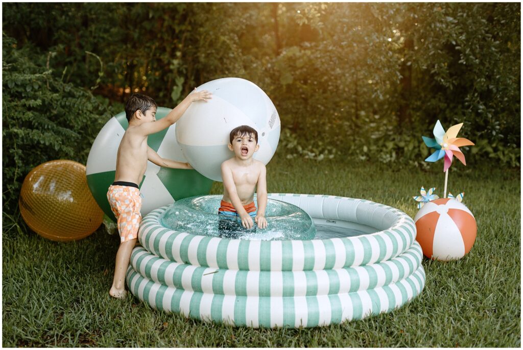 Boys giggling while playing with water and blow-up balls in the yard