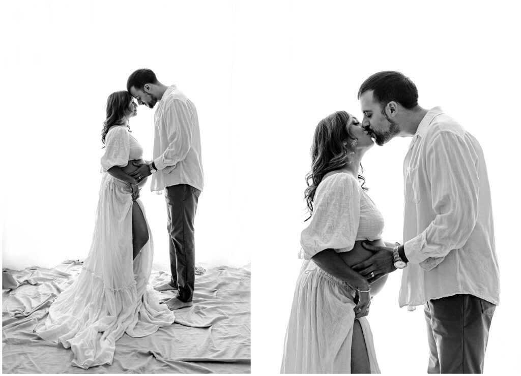 Black and white portraits of pregnant woman in two piece white skirt and top kissing husband while standing and holding belly at Vibe Studio Spring Hill in Florida