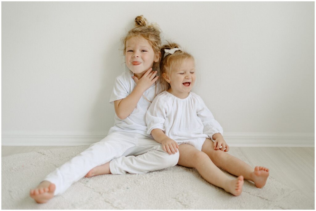 Siblings being silly while sitting on floor and making faces