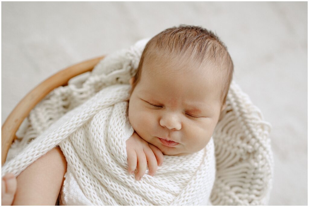 Close up portrait of swaddled newborn baby in basket