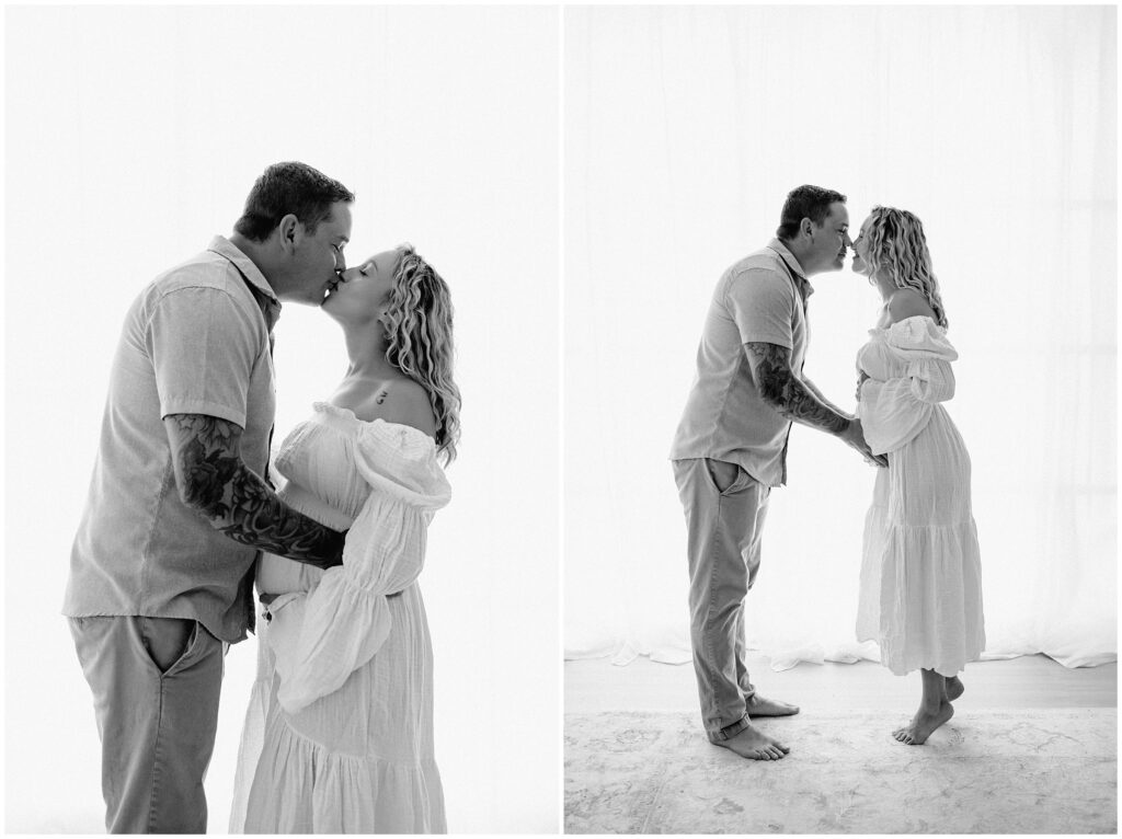 Black and white portrait of pregnant couple kissing in white dress and khaki pants at Spring Hill studio