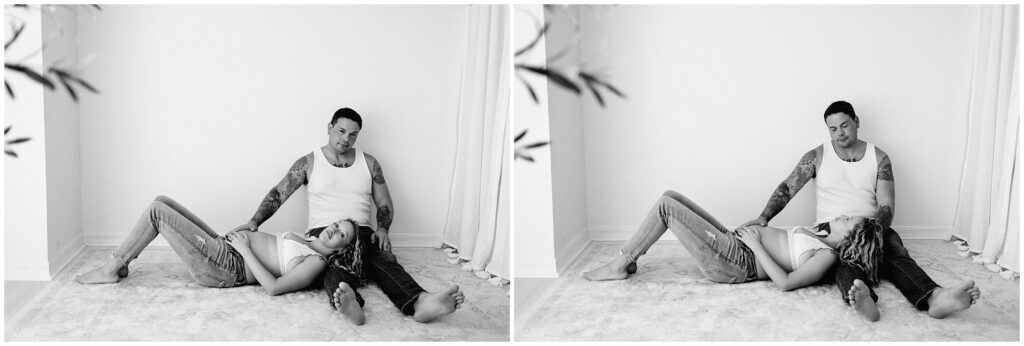 Black and white portrait of husband and wife while pregnant in jeans and white tops, snuggling barefoot on the floor at Spring Hill Studio in Florida.
