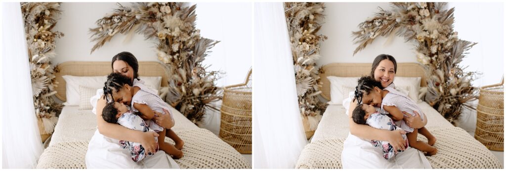 Mom and two daughters kissing on bed newborn session at Spring Hill Studio in Florida