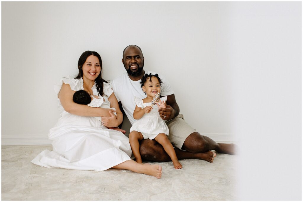 Family of 4 sitting on floor during newborn session at Spring Hill Studio in Florida